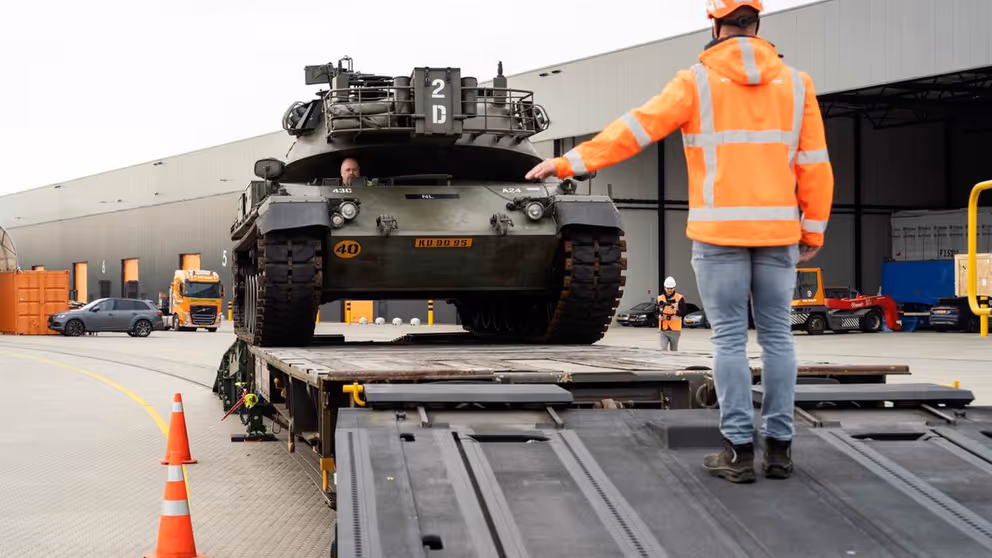 Militair voertuig wordt op een wagon gereden.