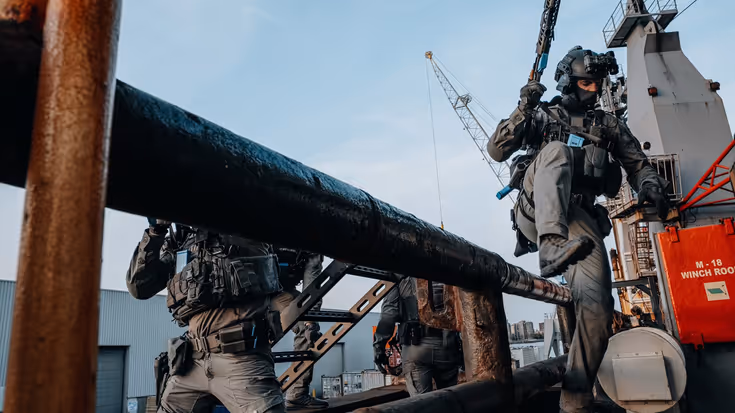 Een militair springt over een hekje. 