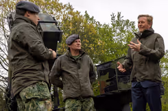 Koning Willem-Alexander in gesprek met 2 militairen. Ze staan voor een Patriot-luchtverdedigingssysteem.