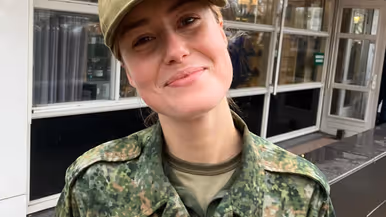 Floor draagt een camouflage-uniform en pet van de Nationale Weerbaarheidstraining.