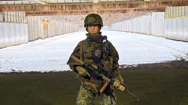 Floor staat in militair tenue met helm en wapen op een schietbaan.