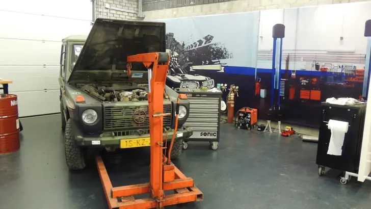Garage met een auto waarvan de voorklep omhoog staat.