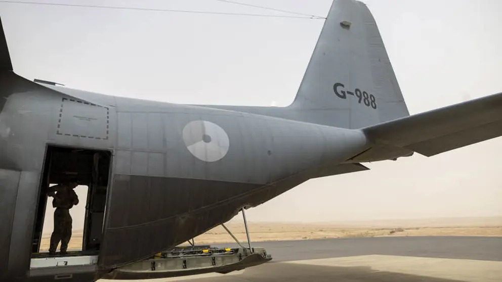 Vliegtuig van de zijkant gezien, met in de deuropening een militair.