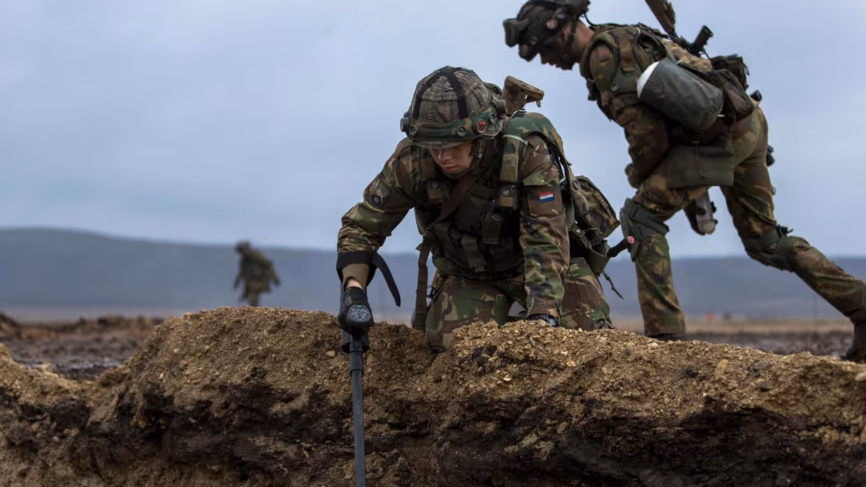 Twee militairen bezig met een metaaldetector.