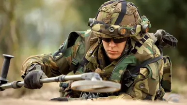 Een militair aan de slag met een metaaldetector.