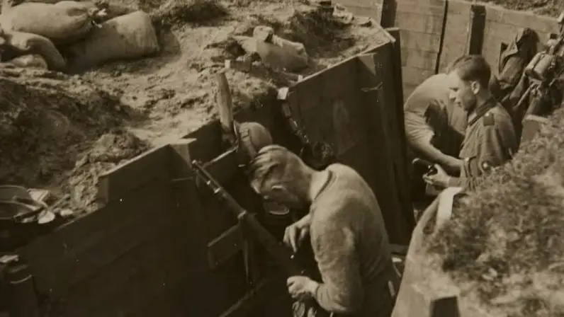 Oude foto in bruintinten van militairen in een loopgraaf die op een niet operationele manier bezig zijn met hun wapen.