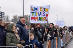 Mensen tonen een spandoek om militairen welkom terug te heten na inzet.