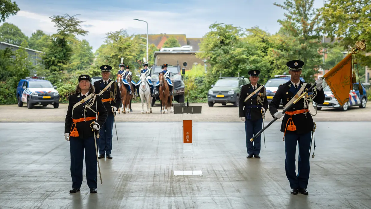 De vertrekkend commandant en de nieuwe staan opgesteld. Luitenant-generaal Costongs staat rechts en heeft de officiële standaard van de Marechaussee vast.