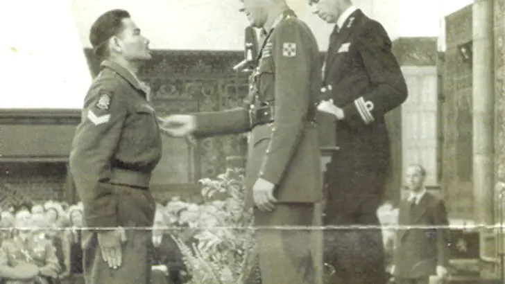 Zwart-wit foto van militair die medaille krijgt van Prins Bernhard.