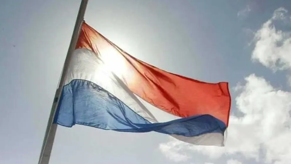 Nederlandse vlag wappert halfstok. 