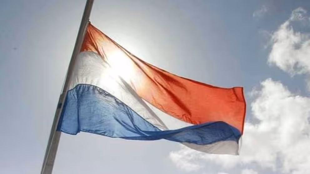 Nederlandse vlag wappert halfstok. 