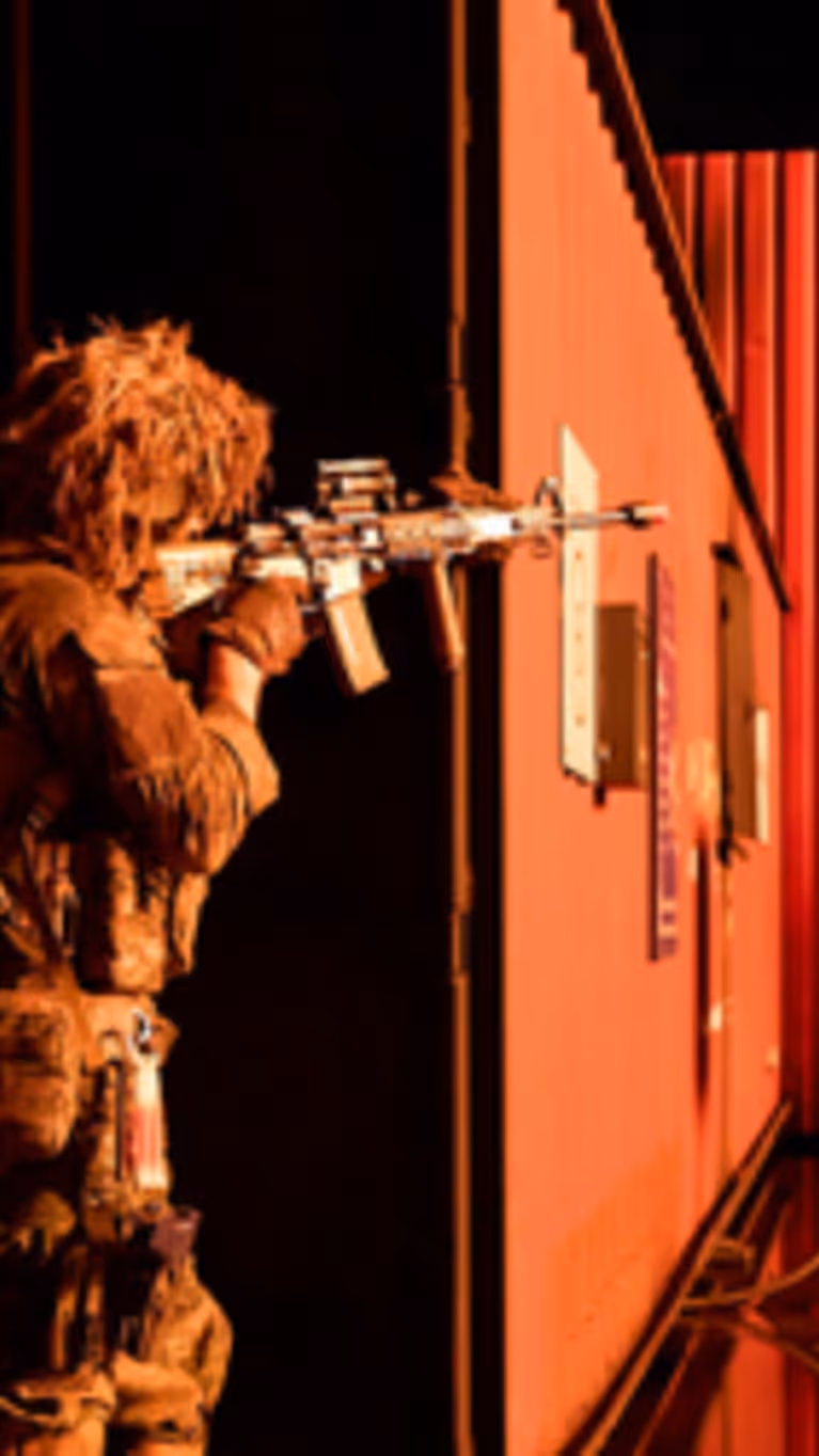 Mariniers bewegen zich langs een container bij nacht en richten hun wapens.