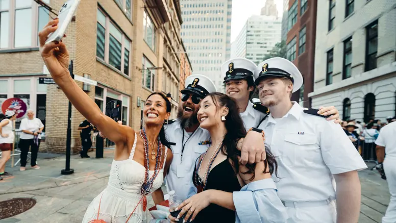 Bemanningsleden in wit uniform laten zich fotograferen met twee New Yorkse dames.