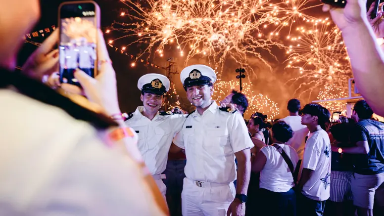 Oplichtend vuurwerk met daarvoor een aantal marinemannen.