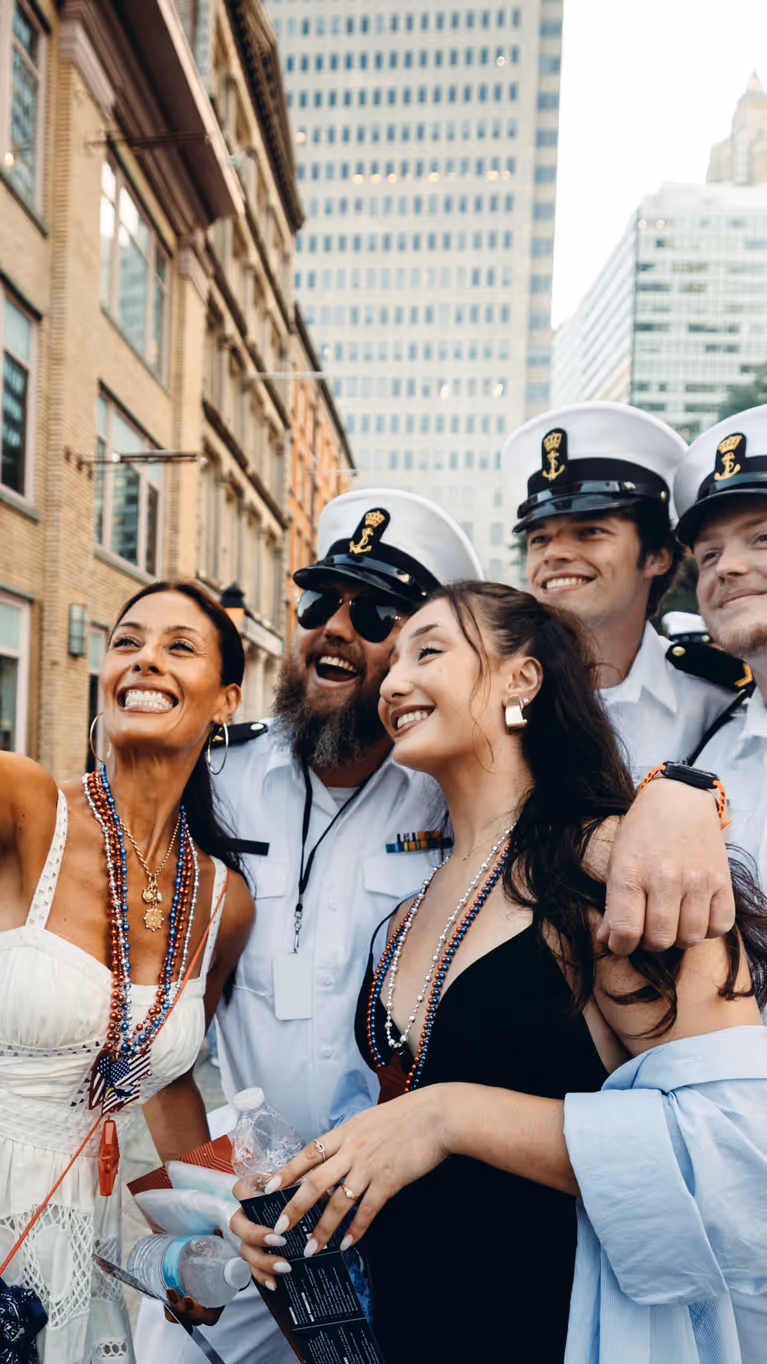 Bemanningsleden in wit uniform laten zich fotograferen met twee New Yorkse dames.