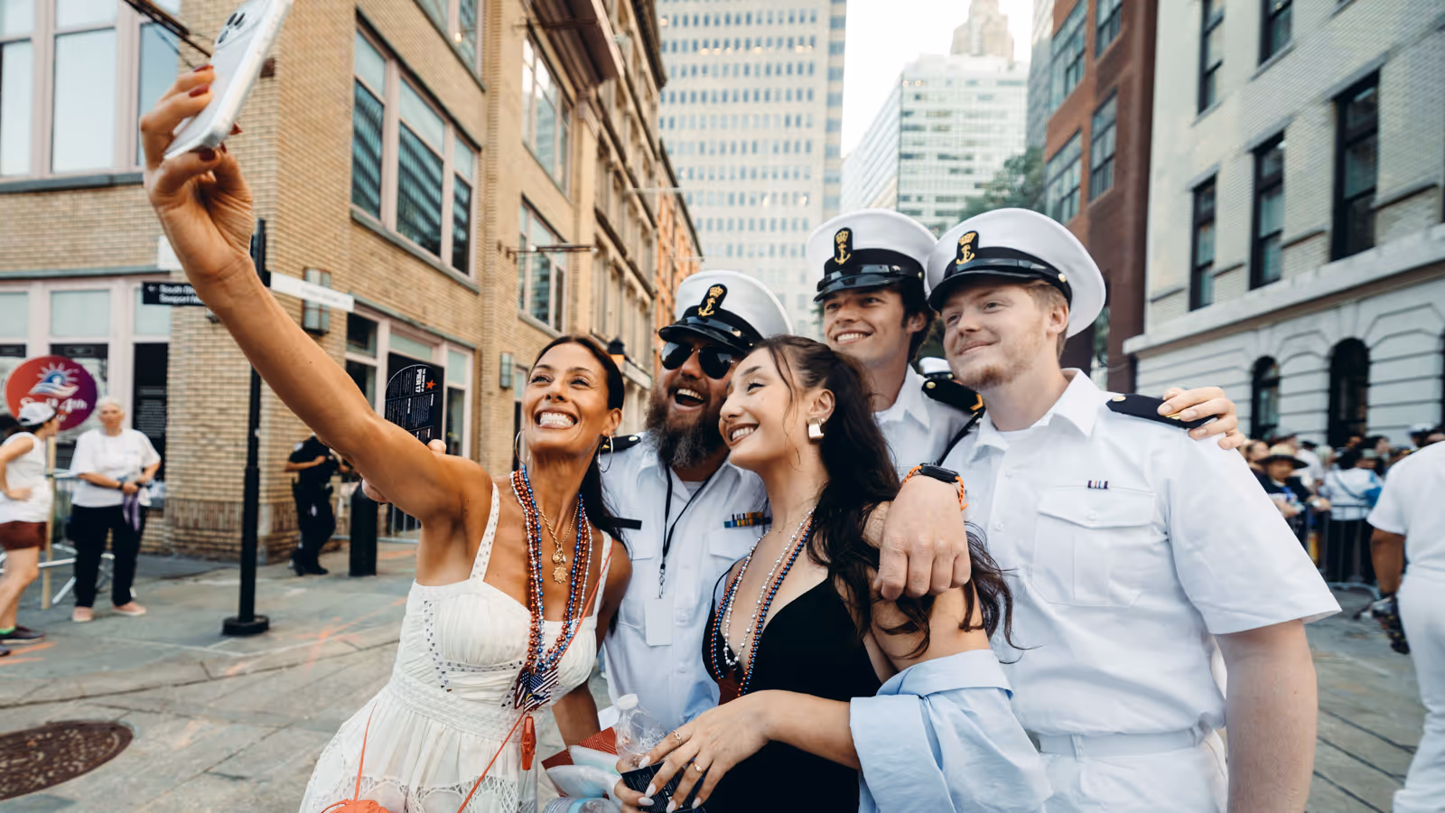 Bemanningsleden in wit uniform laten zich fotograferen met twee New Yorkse dames.