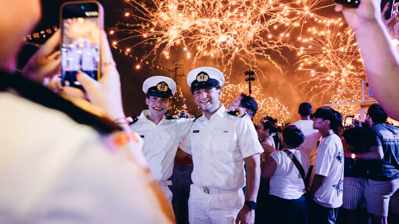 Oplichtend vuurwerk met daarvoor een aantal marinemannen.