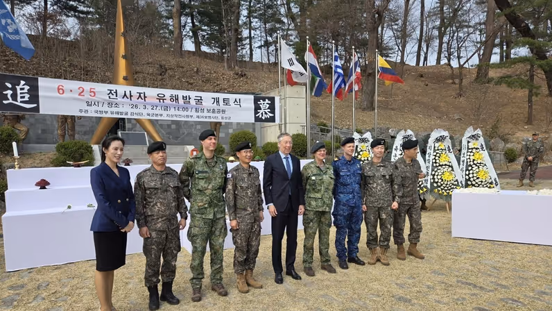 Een groep militairen staat opgesteld. Met Leon Diender met tenue 6 in het midden. Achter hen is een banier te zien met Koreaanse tekens.