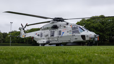 Een Chinook stijgt op boven een veld, met aan een lange kabel de Nederlandse vlag