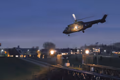 Helikopter bij schemer boven bewoond gebied.