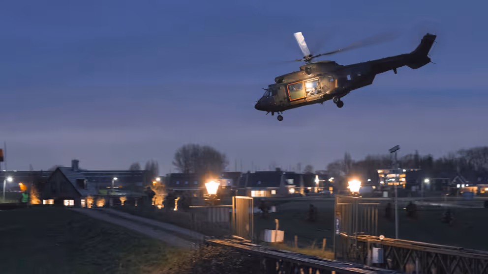 Helikopter bij schemer boven bewoond gebied.