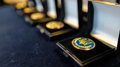 Rij opengeklapte doosjes met daarin ieder een blauw-gele medaille.