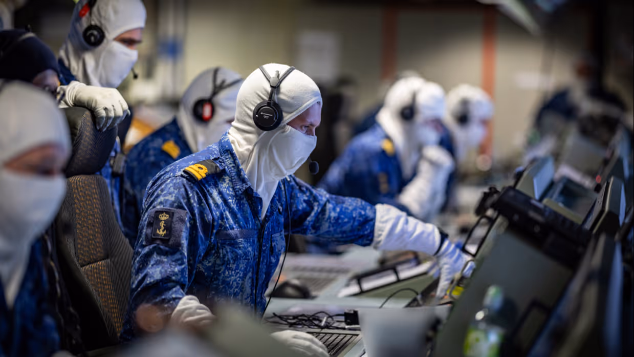De bemanning zit aan de knoppen in het schip.  