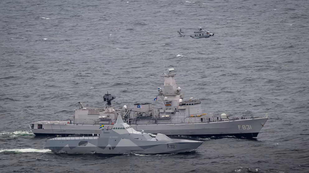 Een Zweedse schip met daarachter de Van Amstel en daarboven een NH90-helikopter.