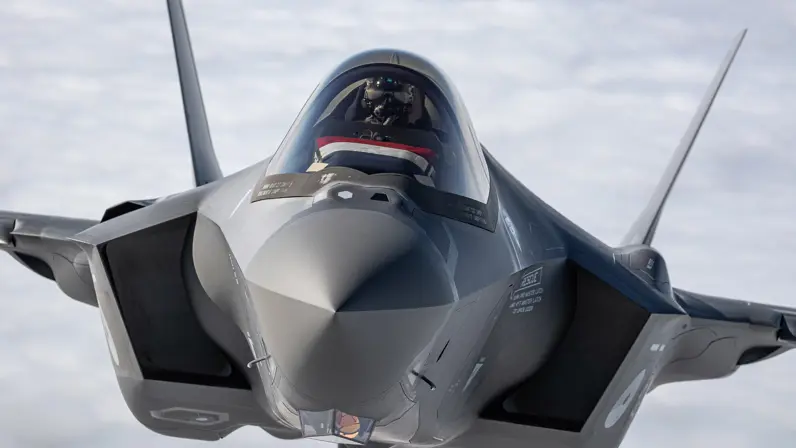 F-35 frontaal in de lucht. In de cockpit ligt een Nederlandse vlag.