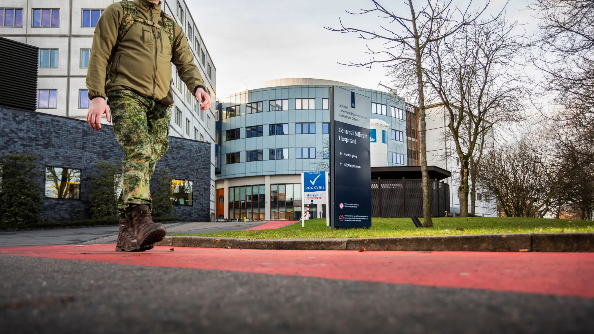 Bord met daarop de naam Centraal Militair Hospitaal en daarnaast op de achtergrond een wapperende Nederlandse vlag.
