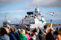Familie en vrienden zwaaien vanaf kade enthousiast naar marineschip dat terugkeert van missie.
