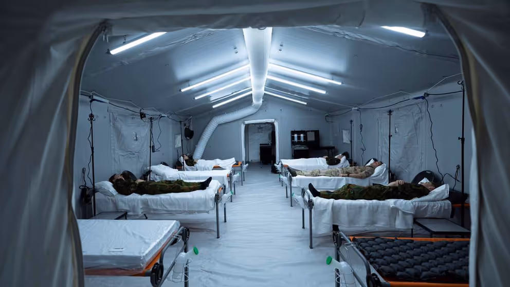 Grote tent met ziekenhuisbedden waarop mensen liggen.