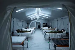 Grote tent met ziekenhuisbedden waarop mensen liggen.