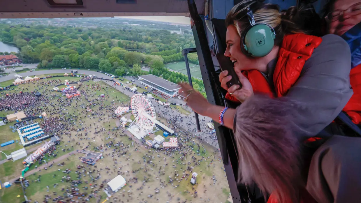  Zangeres Maan zwaait door de open deur van een vliegende heli naar publiek op het festivalterrein onder hen.