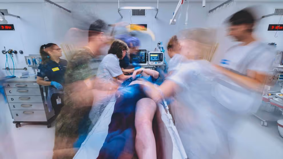 Hulpverleners rond een ziekenhuis bed. Foto lijkt bewogen om de hectiek aan te geven.