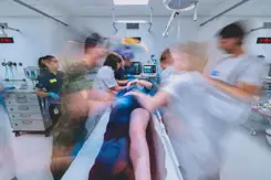 Hulpverleners rond een ziekenhuis bed. Foto lijkt bewogen om de hectiek aan te geven.