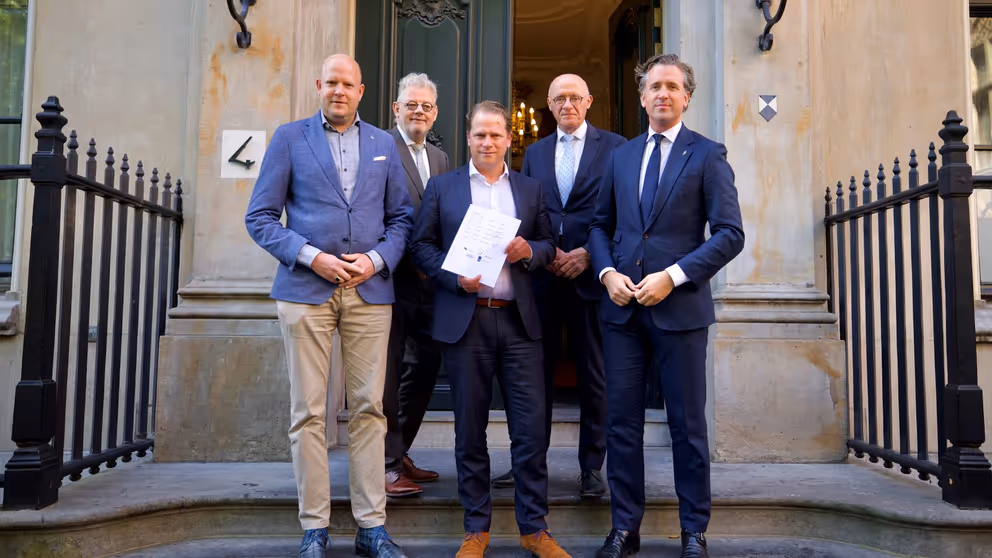 De staatssecretaris poseert met 4 mannen op de trap van het ministerie.