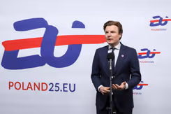 Minister Brekelmans voor een wit bord met blauwe en rode tekst: EU Poland25.EU