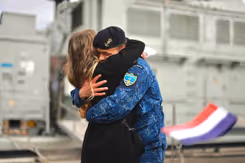 Marineman omhelst vrouw. Op de voorgrond Nederlands vlaggetje.