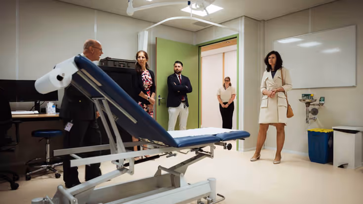 5 personen bekijken nieuwe behandelkamer met behandelstoel in het midden.