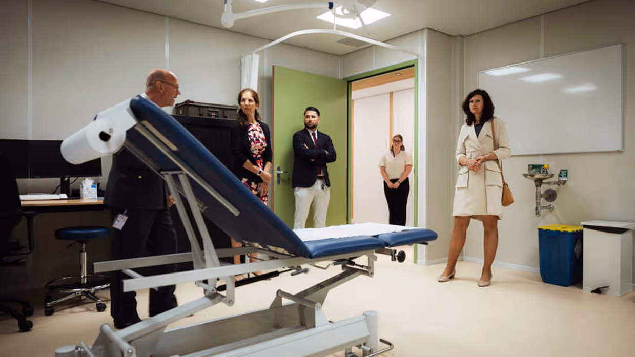 5 personen bekijken nieuwe behandelkamer met behandelstoel in het midden.