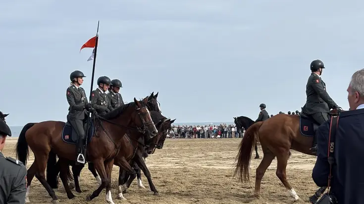 De ruiters met hun paarden op het strand. 