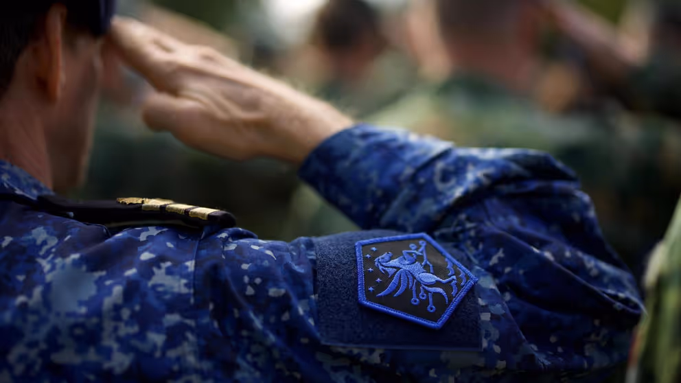 Een militair met het logo van JFC op het uniform brengt een groet uit.