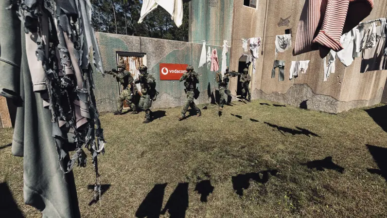 Mariniers lopen langs wasgoed dat in een tuin van een oefenhuis is opgehangen.  
