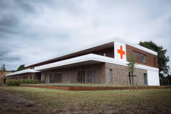Buitenkant militair Gezondheidscentrum en Tandheelkundig Centrum met rood kruis op de buitenmuur.