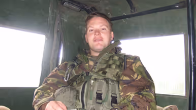 Een jonge Tim Nelissen in gevechtstenue zittend achterin in een militair voertuig. Hij kijkt in de camera.