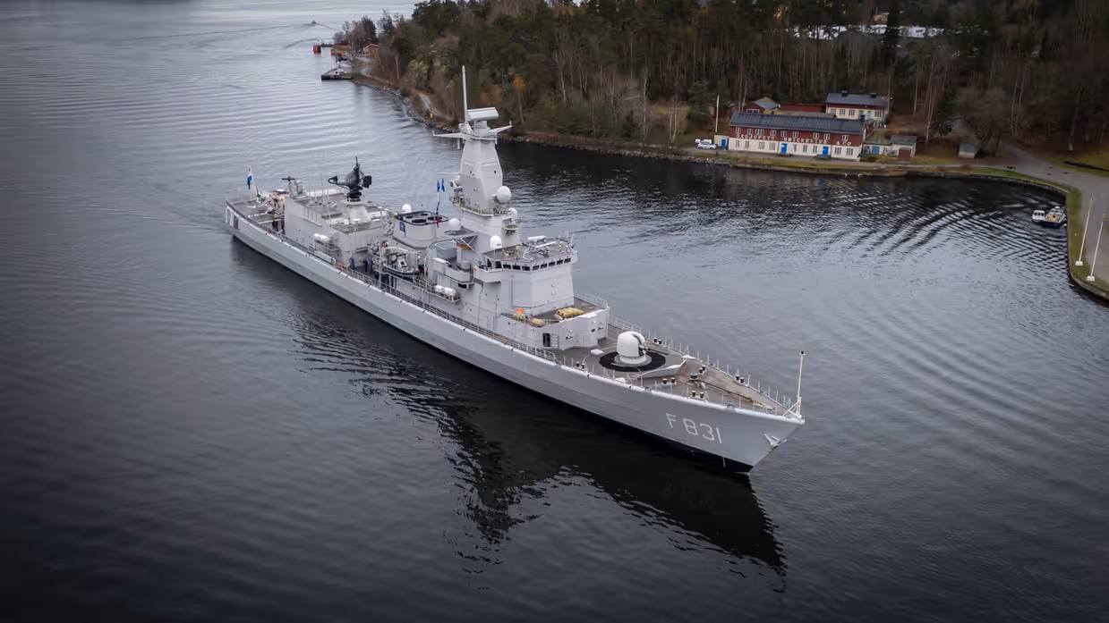 Een militair schip is zichtbaar langs de kust.