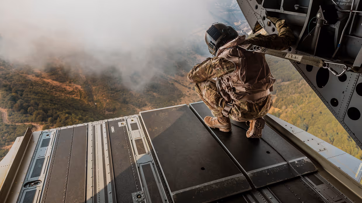 Militair kijkt vanuit helikopter naar een bosbrand