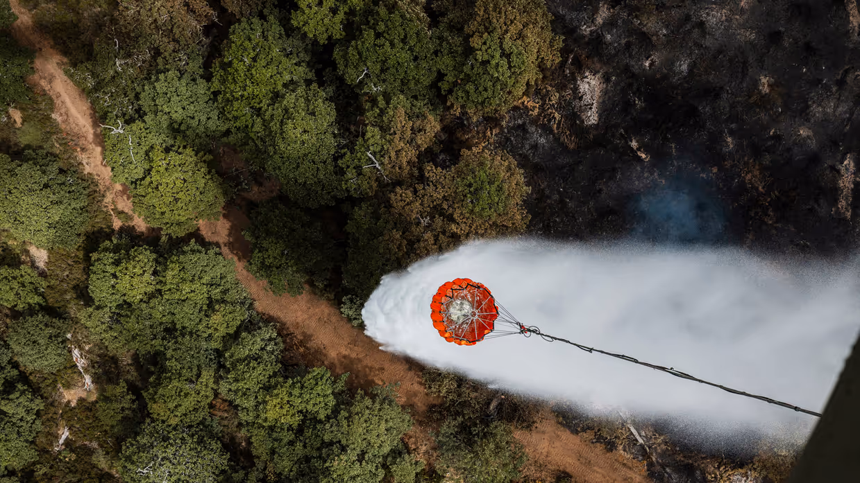 Helikopter schept water uit een rivier om mee te blussen