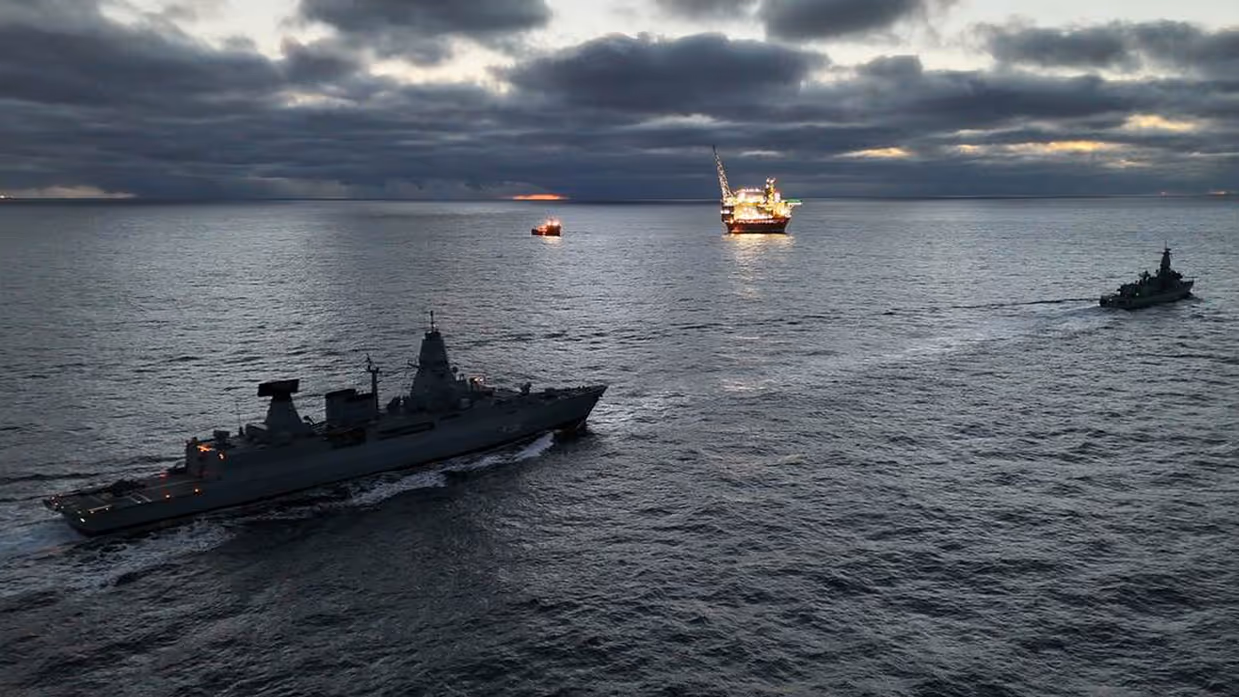 Militaire schepen varen langs andere fel belichte schepen.